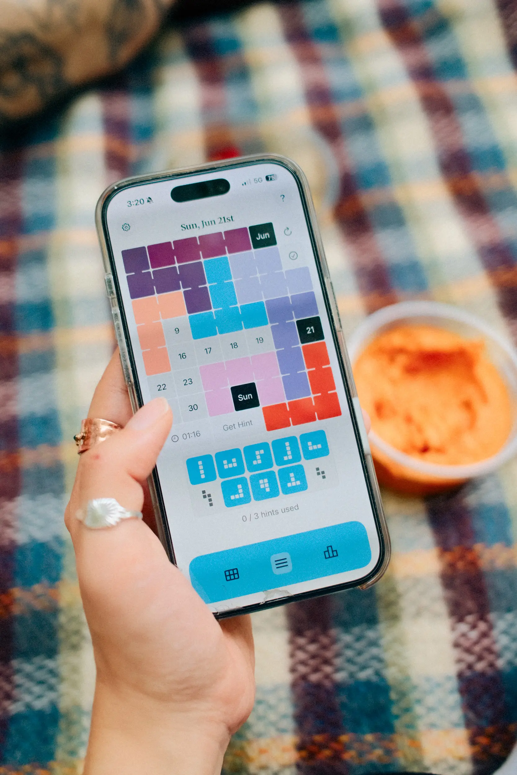photo of two people in a coffee shop, one playing the digital calendar puzzle game and one playing the physical game.