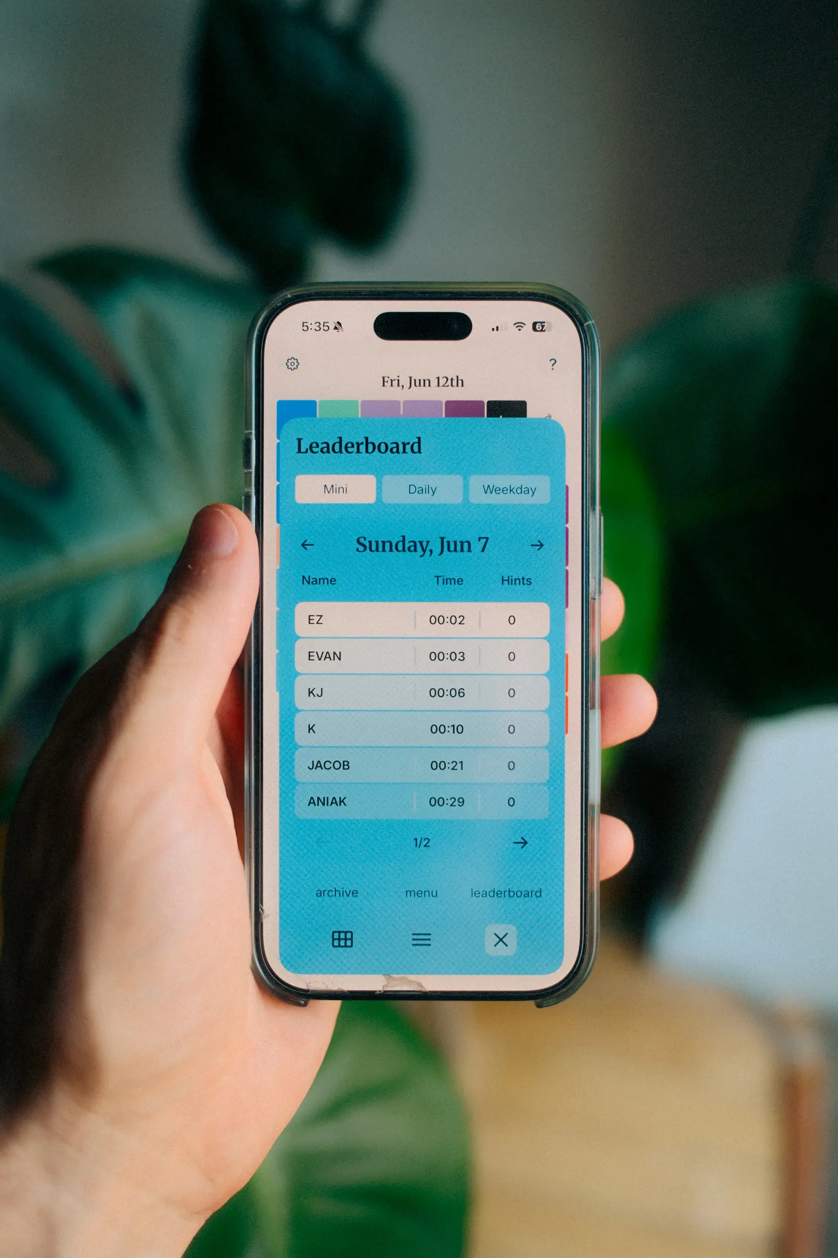 Photo of someone's hand holding up a phone with the calendar puzzle app open, showing the leaderboard page.